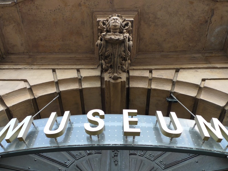 Museumsschild über dem Hauptportal mit Sandsteinfigur