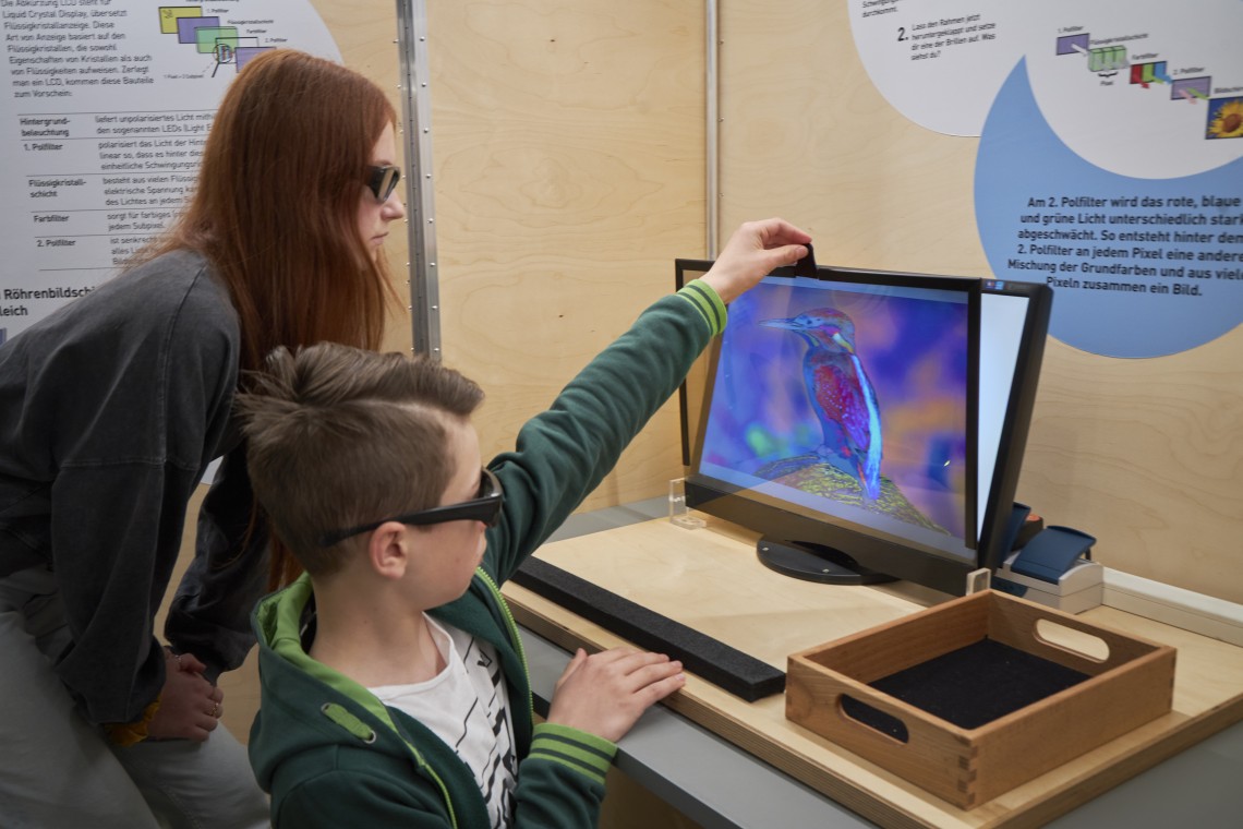Ein Junge und ein Mädchen experimentieren mit einem LCD-Bildschirm und einem Polfilter