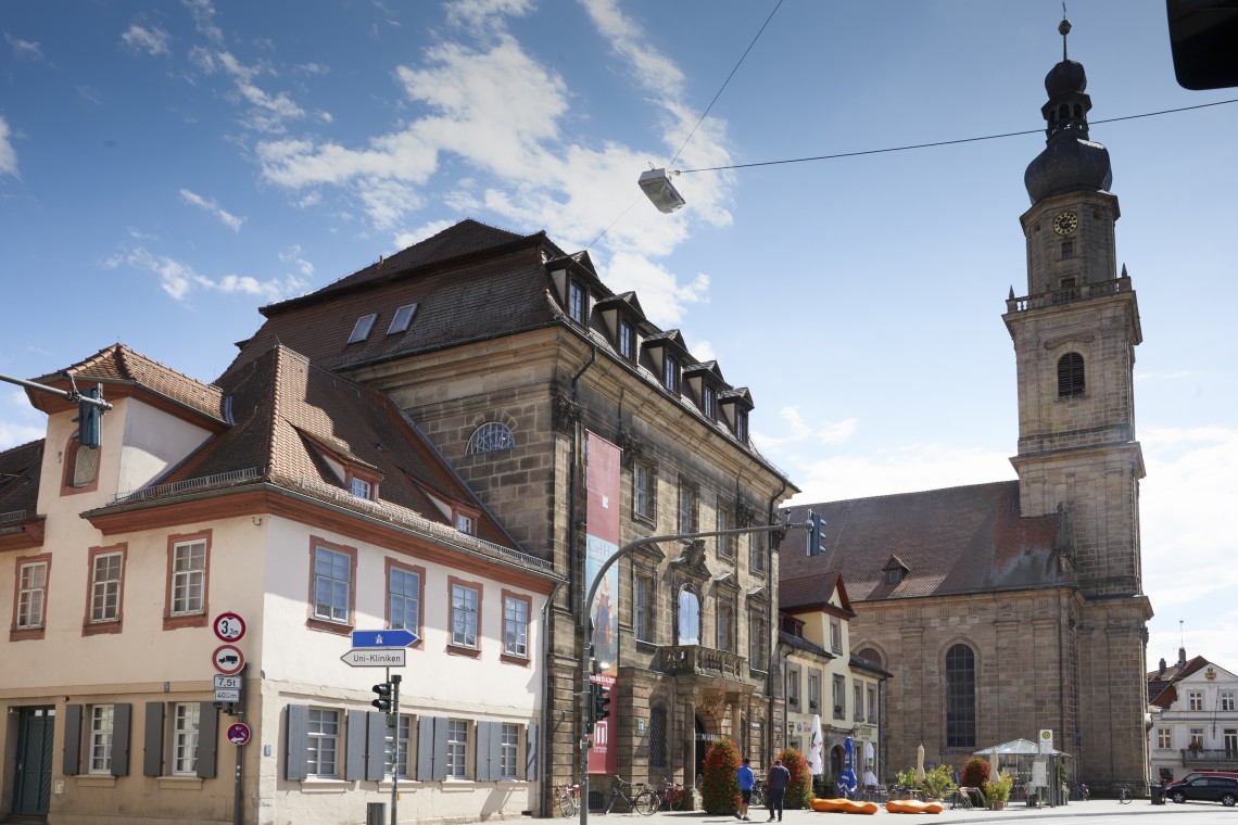 Das Bild zeigt drei Gebäude des künftigen Museumskarrees, das ehemalige Altstädter Rathaus sowie zwei Bürgerhäuser am Martin-Luther-Platz. Im Hintergrund ist die Altstädter Dreifaltigkeitskirche zu sehen.